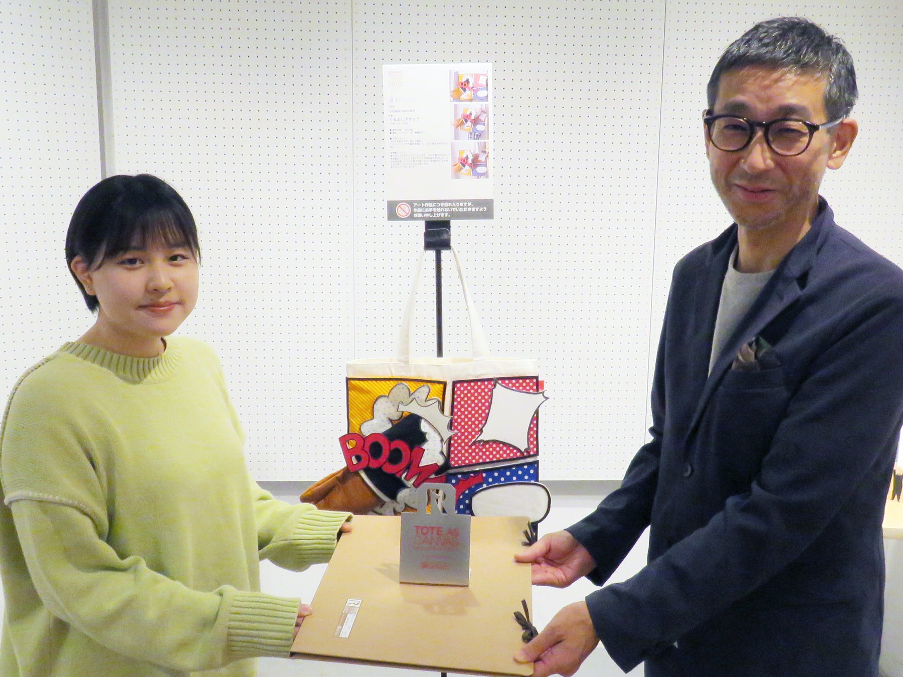 一般公募によるアートなトートバッグ作品のコンテスト！本年度受賞作品展、10/25まで開催中。「第19回 トート・アズ・キャンバス アート&デザインアワード by ROOTOTE」プレビューレポートのサブ画像7_準グランプリ作品「shake hands!!」作者のくるぶしアタックさんを表彰。左 くるぶしアタックさん、右 株式会社ルートート 代表取締役 神谷富士雄