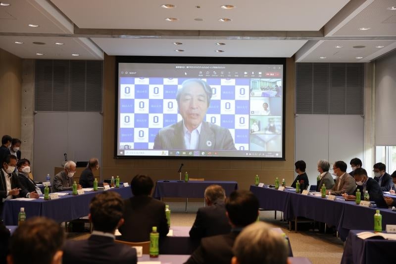 【岡山大学】共同研究「瀬戸内サステナビリティ＆ウェルビーイング研究プロジェクト」最終報告会 －ベネッセアートサイト直島/瀬戸内国際芸術祭のインパクトとモデルとしての可能性－を開催しましたのサブ画像2_あいさつする槇野博史学長（WEB参加：正面スクリーン）